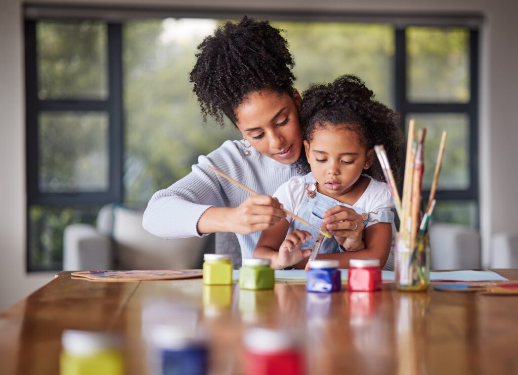 Learning, mother and child painting for an art preschool project with a young mom helping her daugh