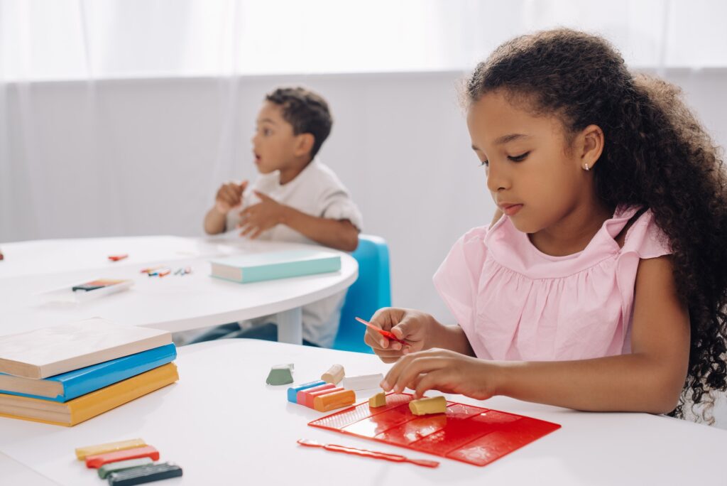 selective focus of african american kid with plasticine sculpturing figure in classroom